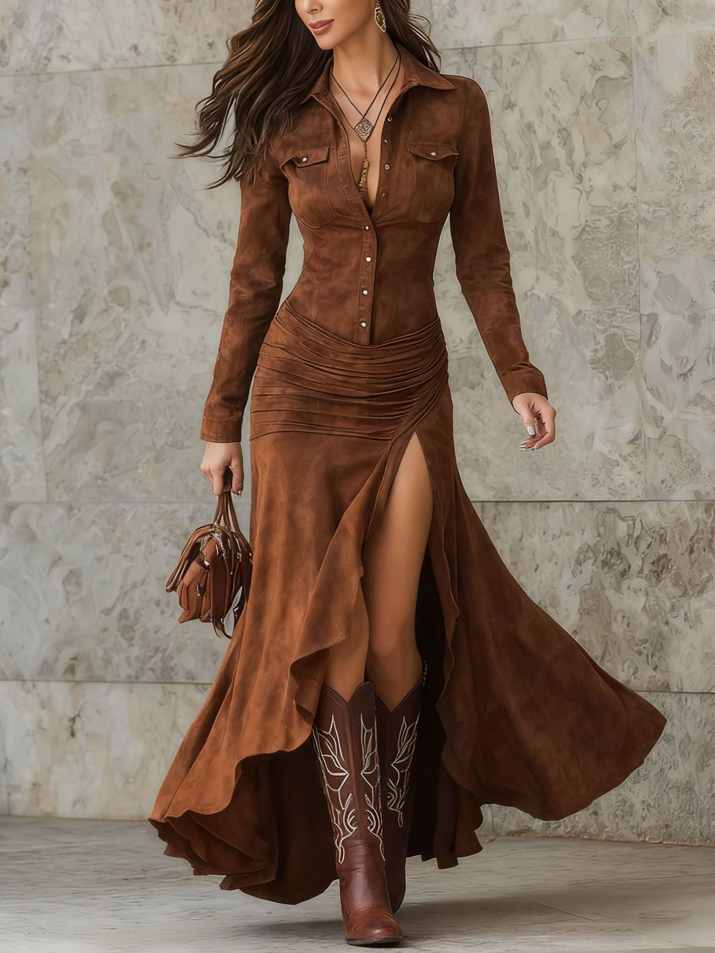Woman wearing a long brown suede dress with a high slit, standing against a stone wall.
