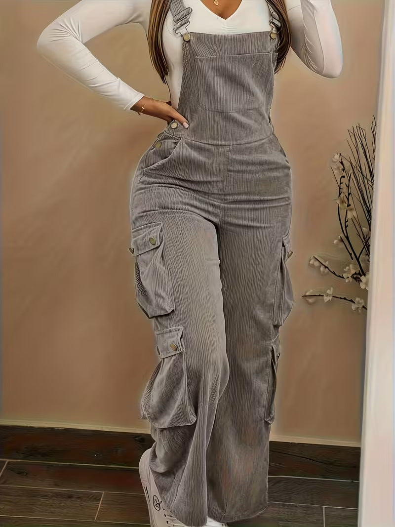 Person wearing gray corduroy overalls with a plain background