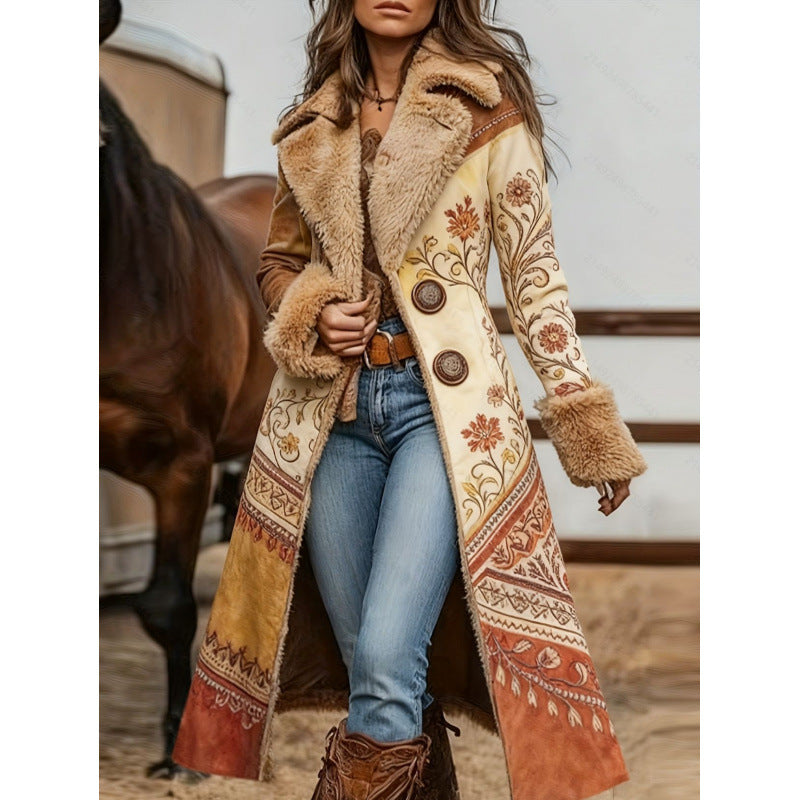 A woman wearing a long western-style coat with faux fur trim, brown leather-like panels, and ornate floral embroidery in tan, rust, and cream. She is standing in a barn-like setting with a horse partially visible in the background.