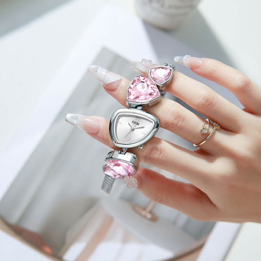 Hand holding a heart-shaped watch with pink gemstones on a blurred background