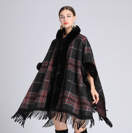 Woman wearing a plaid poncho with fringe on a gray background